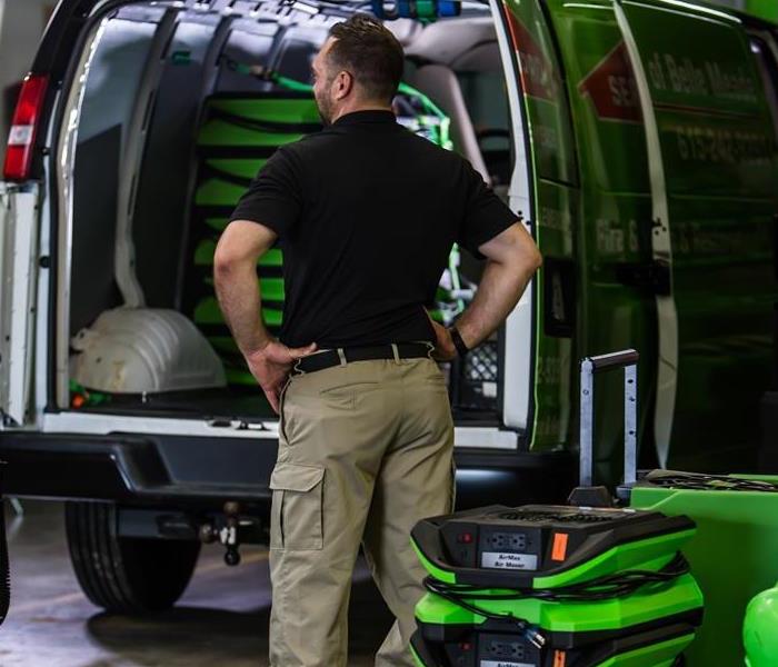 Male employee standing in front of the SERVPRO van prepping with equipment to go out on the scene!